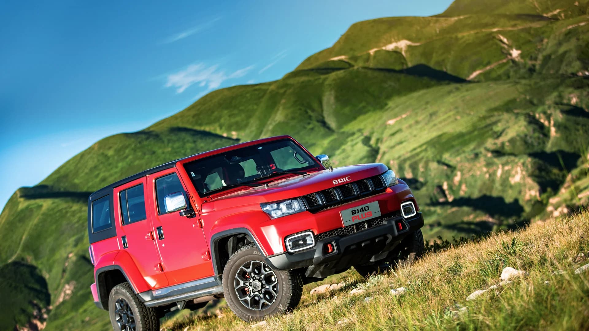 Red BAIC BJ40 Plus on a green mountainside