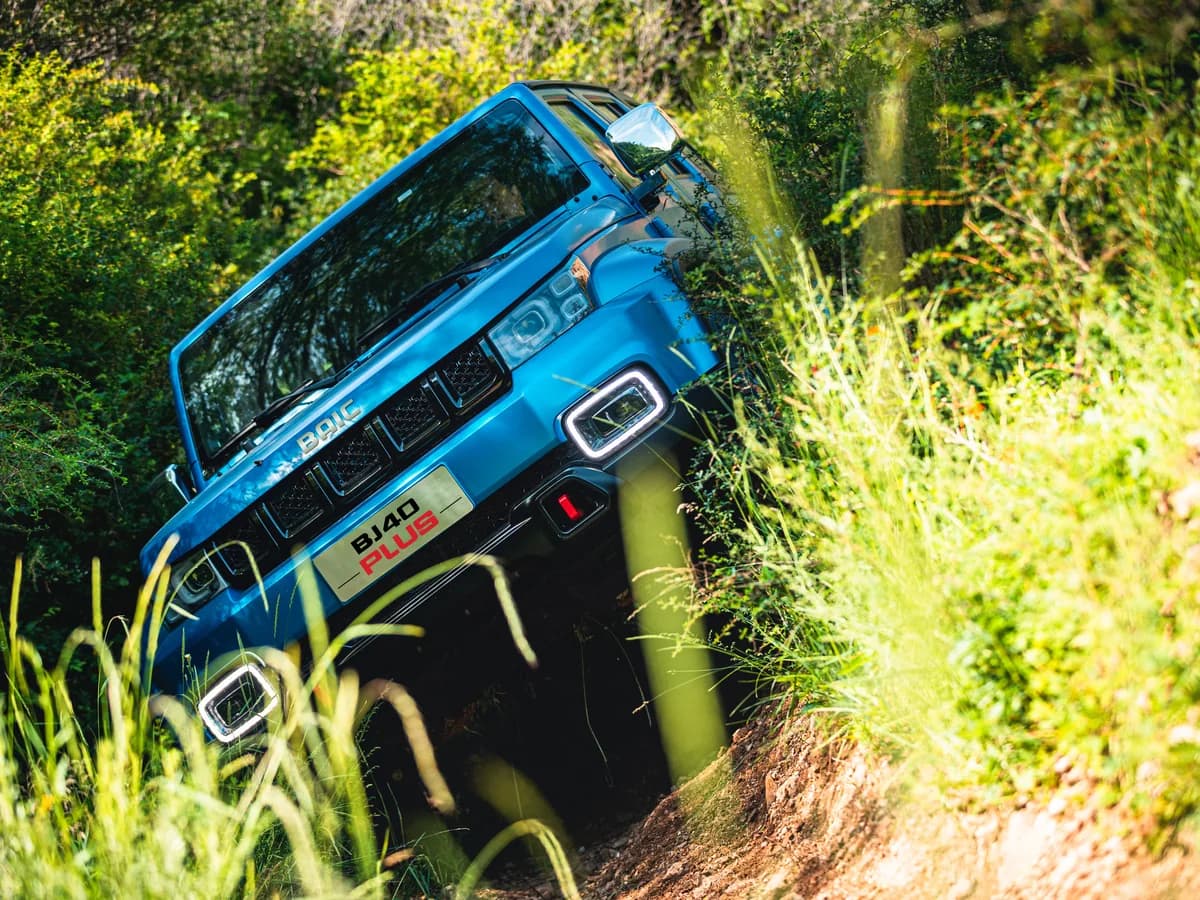 Blue BAIC BJ40 Plus descending a steep grass slope