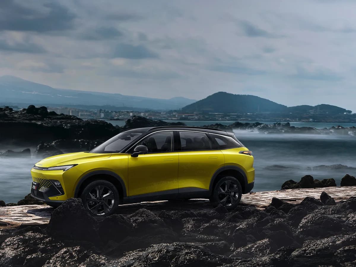 Lemon Yellow BAIC X55 II in profile on a rocky coastline
