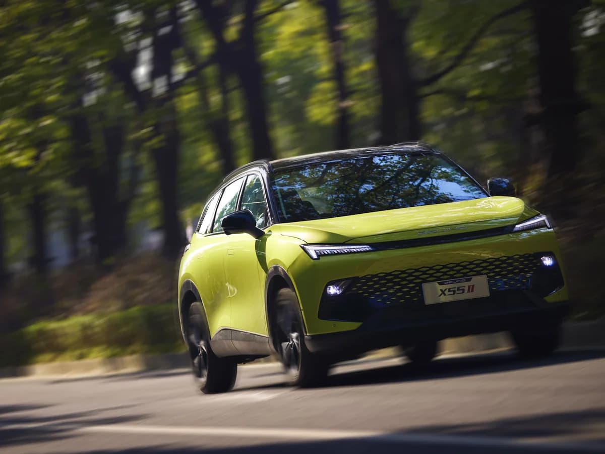 Lemon Yellow BAIC X55 II driving on a tree-lined road