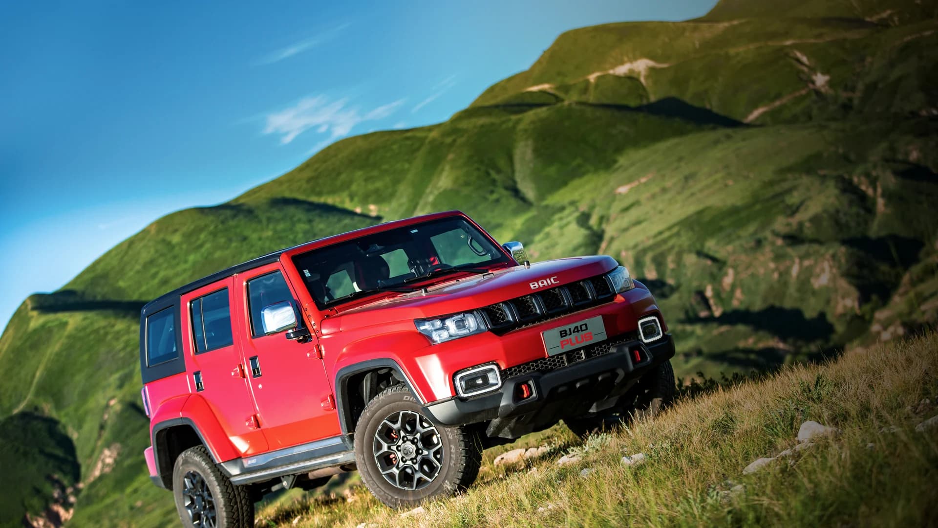 Red BAIC BJ40 Plus on a green mountainside